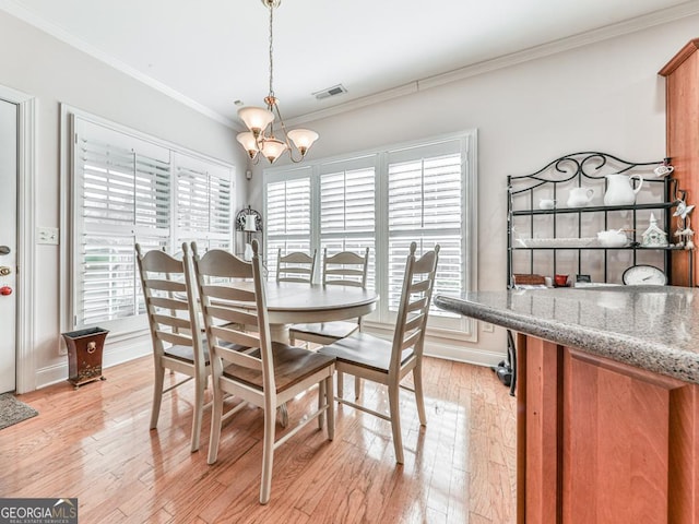 dining room featuring crown molding, light hardwood / wood-style flooring, and a notable chandelier