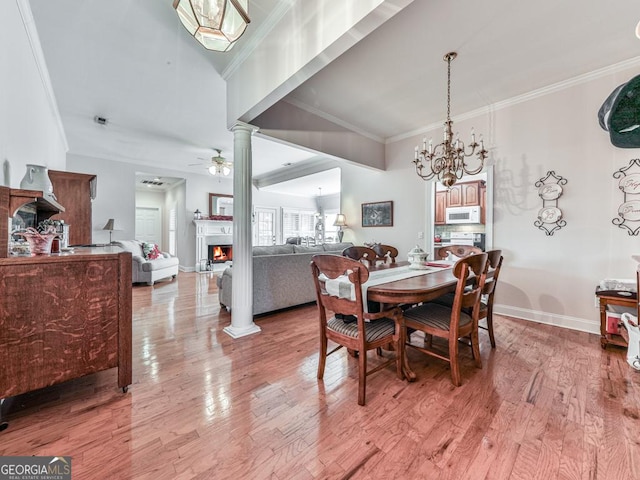 dining area featuring decorative columns, crown molding, ceiling fan with notable chandelier, and hardwood / wood-style flooring