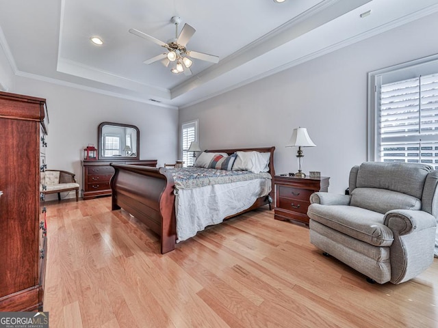 bedroom featuring ceiling fan, light hardwood / wood-style floors, a raised ceiling, and ornamental molding