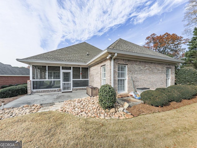 back of property featuring a sunroom, a patio area, and a lawn