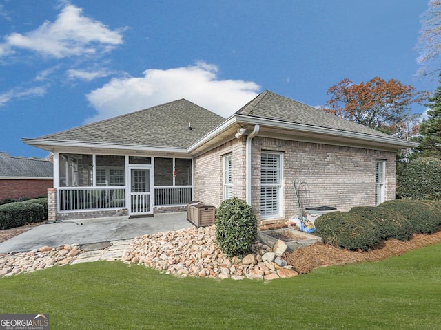 back of property featuring a sunroom, a patio, and a lawn