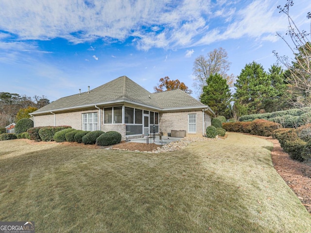 back of property with a lawn, a sunroom, and a patio