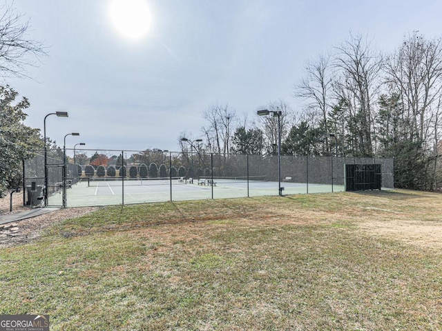 view of tennis court featuring a lawn