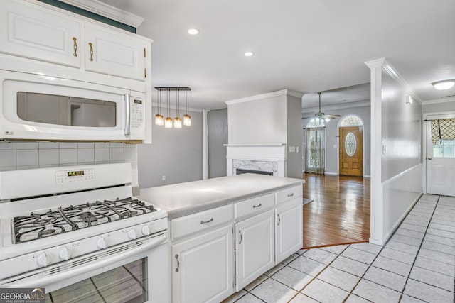 kitchen featuring white appliances, crown molding, hanging light fixtures, a premium fireplace, and white cabinetry