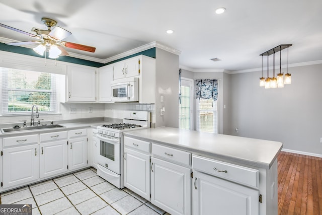 kitchen with kitchen peninsula, white cabinets, light hardwood / wood-style floors, and white appliances