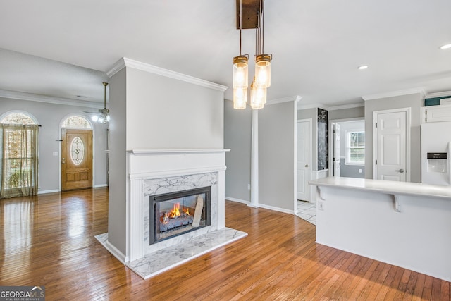 unfurnished living room featuring a fireplace, crown molding, light hardwood / wood-style flooring, and ceiling fan