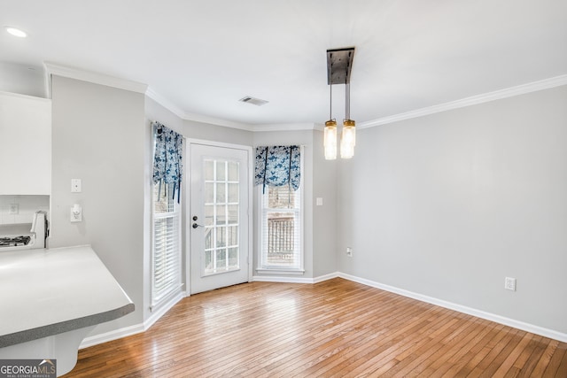 unfurnished dining area featuring hardwood / wood-style floors and crown molding