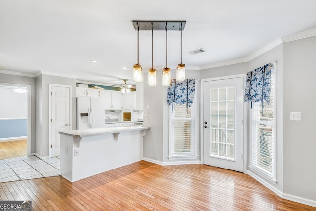 kitchen with a kitchen breakfast bar, kitchen peninsula, light hardwood / wood-style flooring, white fridge with ice dispenser, and white cabinetry