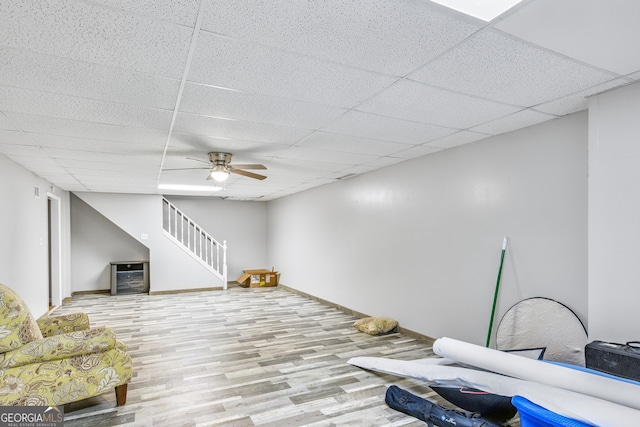 interior space with a paneled ceiling, ceiling fan, and light hardwood / wood-style floors