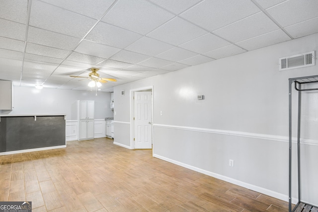 basement featuring a drop ceiling, light hardwood / wood-style floors, and ceiling fan