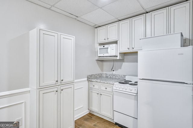 kitchen with white cabinets, hardwood / wood-style floors, white appliances, and a paneled ceiling