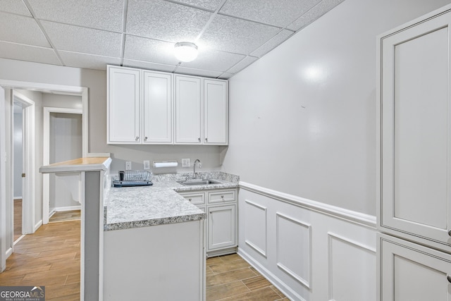 kitchen featuring white cabinets, a drop ceiling, light hardwood / wood-style floors, and sink