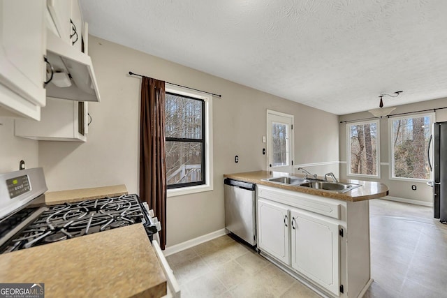 kitchen with sink, appliances with stainless steel finishes, a textured ceiling, white cabinets, and kitchen peninsula