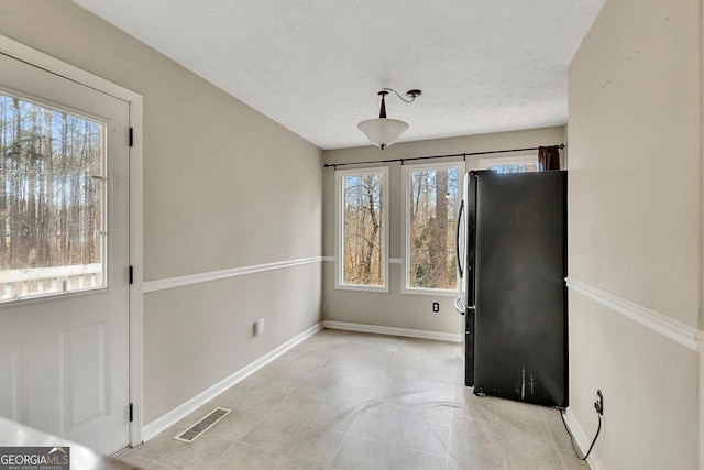 unfurnished dining area featuring a wealth of natural light and a textured ceiling