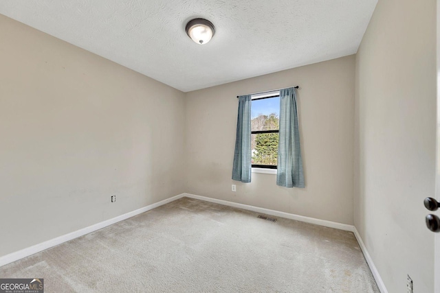 carpeted empty room featuring a textured ceiling