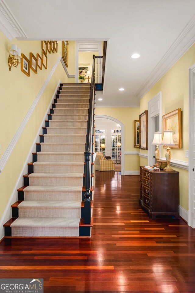 staircase with wood-type flooring and ornamental molding