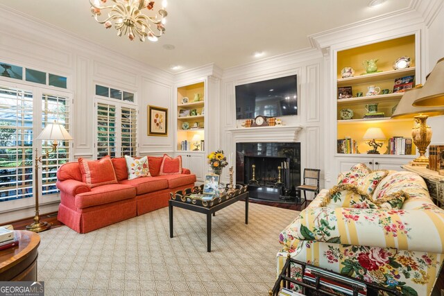 living room featuring built in shelves, an inviting chandelier, a high end fireplace, ornamental molding, and light wood-type flooring