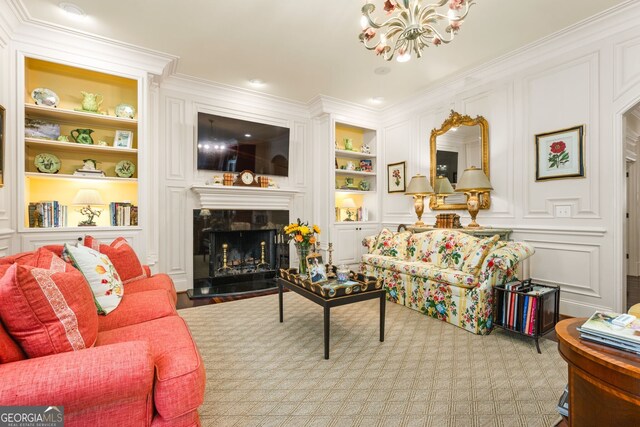 living room with built in shelves, crown molding, a fireplace, and a chandelier