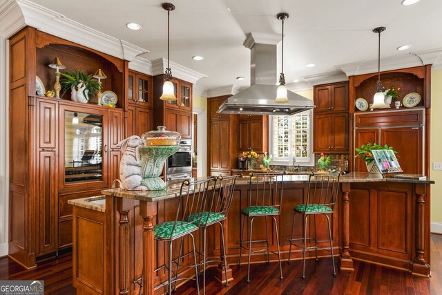 kitchen with island range hood, dark wood-type flooring, hanging light fixtures, and light stone counters