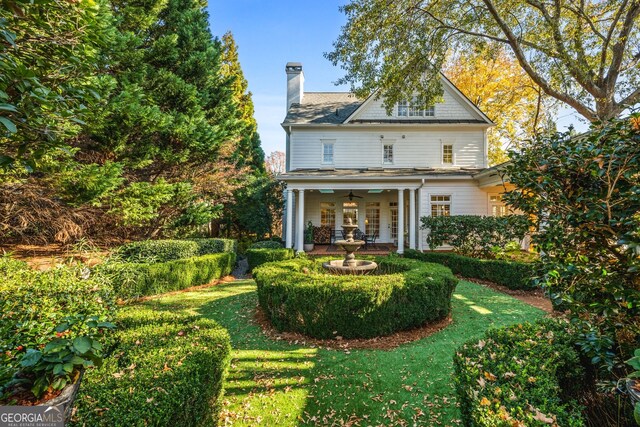 rear view of property featuring ceiling fan and a lawn