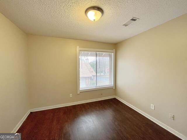 1153 Village Main St, Stone Mountain, GA 30088 - spare room featuring dark wood-style floors, visible vents, a textured ceiling, and baseboards
