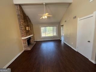 1153 Village Main St, Stone Mountain, GA 30088 - unfurnished living room with dark wood-type flooring, a fireplace, visible vents, baseboards, and beam ceiling