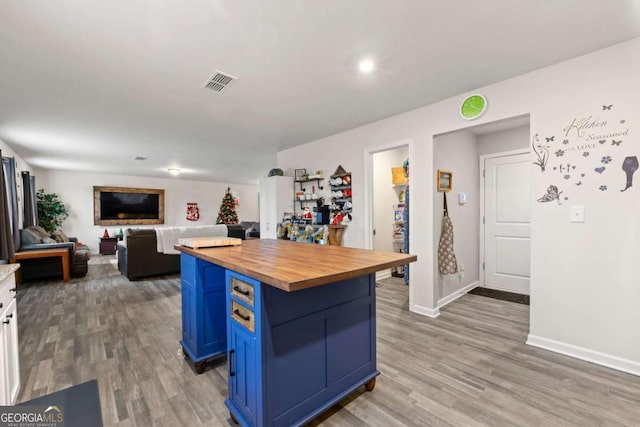 kitchen with a center island, wooden counters, white cabinets, hardwood / wood-style flooring, and blue cabinetry