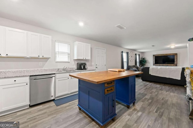 kitchen with a center island, white cabinets, stainless steel dishwasher, and wood counters