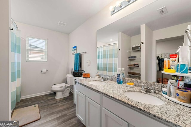 bathroom with hardwood / wood-style floors, vanity, toilet, and walk in shower