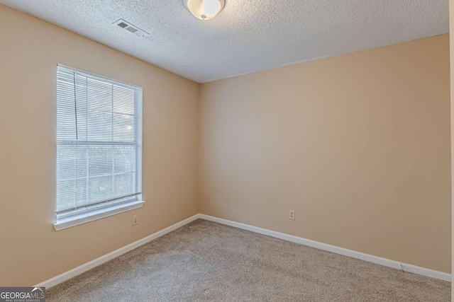 unfurnished room with a textured ceiling and light carpet