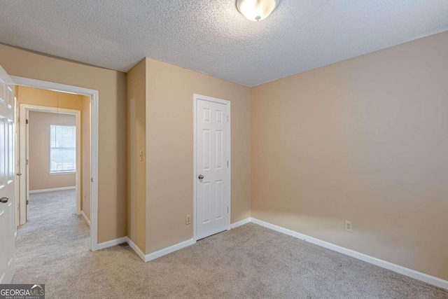 unfurnished bedroom with light carpet, a closet, and a textured ceiling