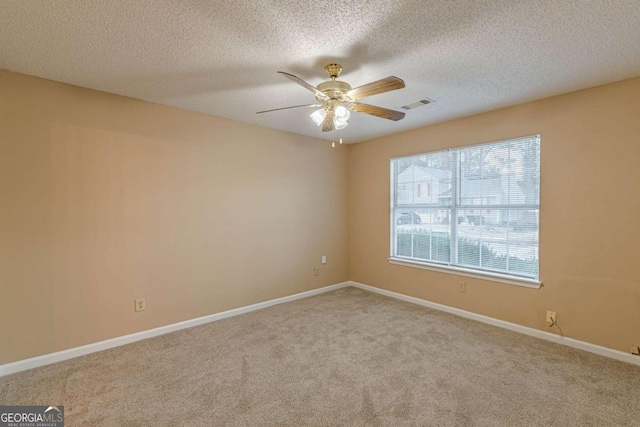 spare room featuring light carpet, ceiling fan, and a textured ceiling