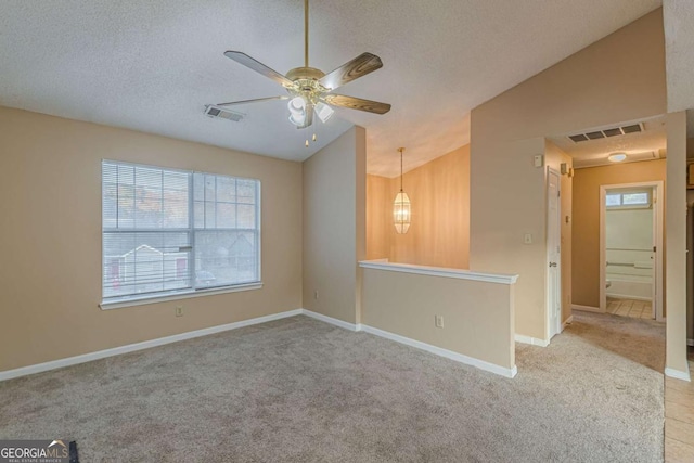 empty room with light carpet, a textured ceiling, ceiling fan, and lofted ceiling