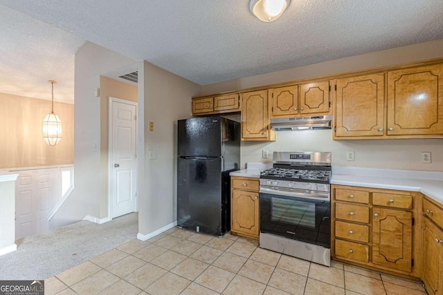 kitchen featuring light tile patterned flooring, black fridge, hanging light fixtures, and stainless steel range with gas stovetop