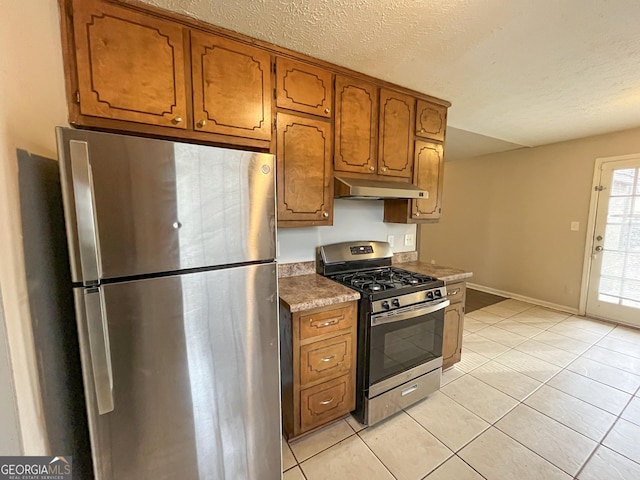 kitchen with light tile patterned flooring, a textured ceiling, and appliances with stainless steel finishes