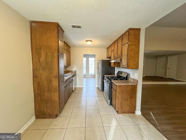 kitchen with gas stove, light tile patterned floors, and a textured ceiling