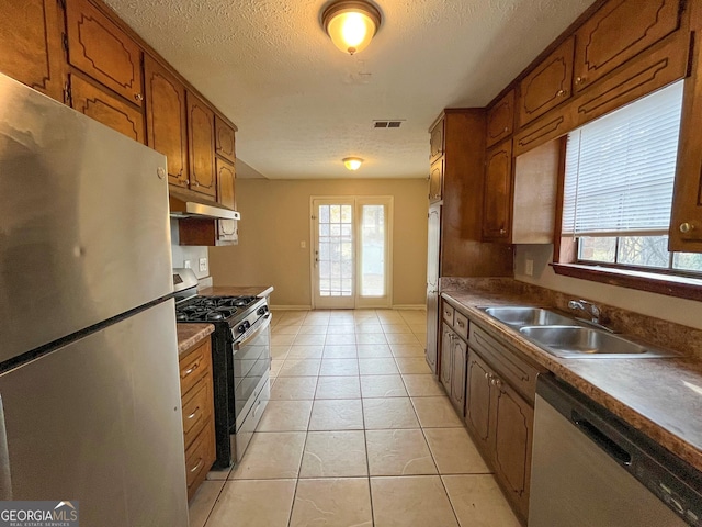 kitchen featuring a textured ceiling, light tile patterned floors, sink, and appliances with stainless steel finishes