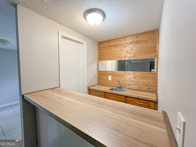 kitchen featuring wood counters, a textured ceiling, tile patterned floors, and sink