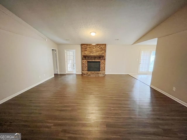 unfurnished living room with a textured ceiling, a fireplace, vaulted ceiling, and dark hardwood / wood-style floors