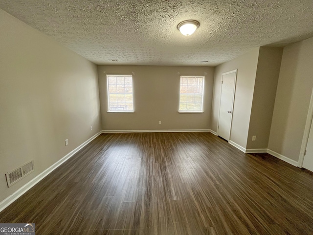 unfurnished room featuring dark wood-type flooring and a textured ceiling