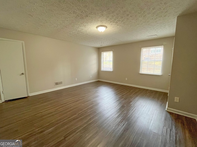 unfurnished room with plenty of natural light, dark wood-type flooring, and a textured ceiling