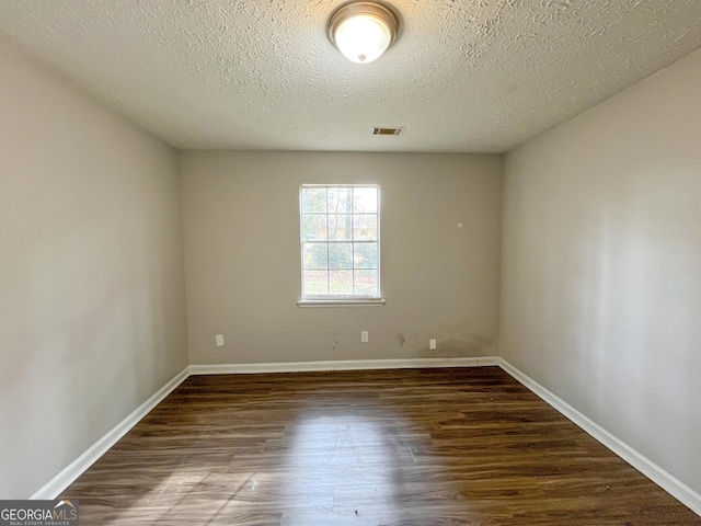 empty room featuring dark wood-type flooring and a textured ceiling