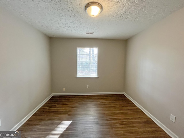 unfurnished room with dark hardwood / wood-style floors and a textured ceiling