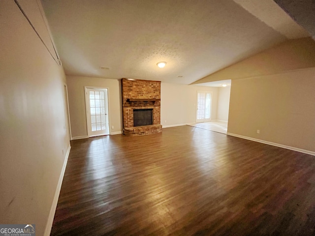 unfurnished living room with a textured ceiling, a fireplace, dark wood-type flooring, and vaulted ceiling