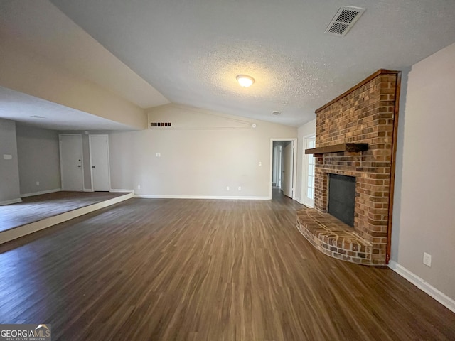 unfurnished living room featuring a textured ceiling, dark wood-type flooring, and vaulted ceiling