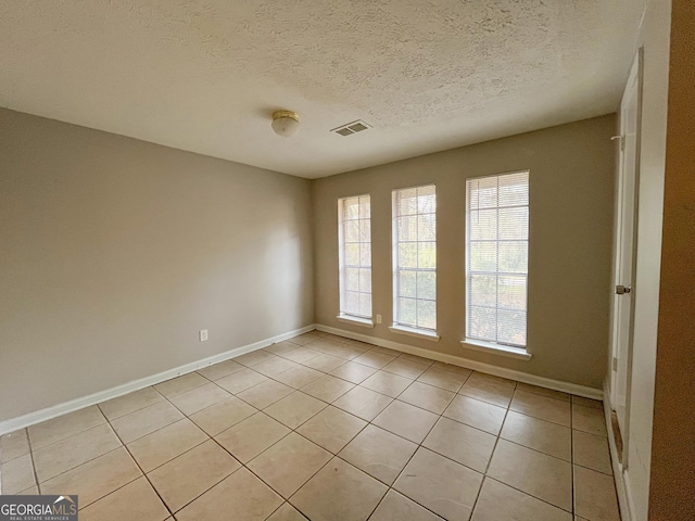 tiled empty room featuring a textured ceiling