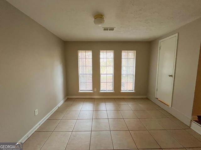 doorway to outside featuring light tile patterned floors and a textured ceiling