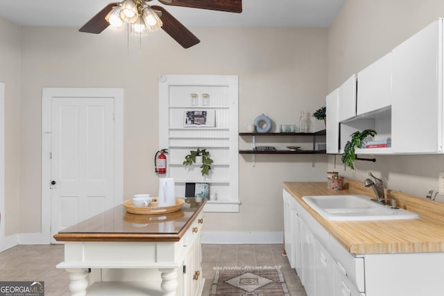 kitchen featuring white cabinets, light tile patterned floors, ceiling fan, and sink