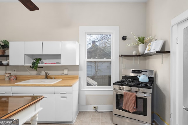 kitchen featuring stainless steel gas range oven, sink, and white cabinets