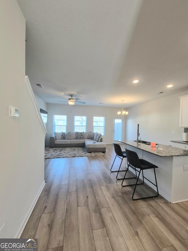 interior space with ceiling fan with notable chandelier, light hardwood / wood-style floors, and sink